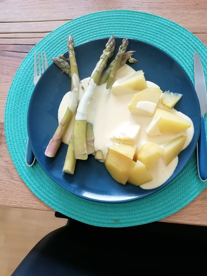 Ein Photo. Ein Teller mit grünem Spargel, Kartoffeln, Sauce hollandaise 