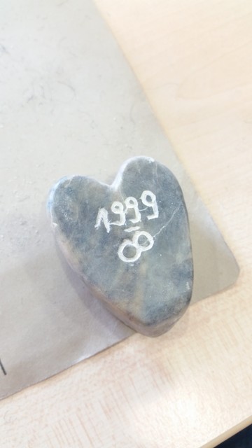 Ein eher dunkel marmorierter Speckstein in Herzform geschliffen. Eingeritzt ist 1999 - unendlich Zeichen 